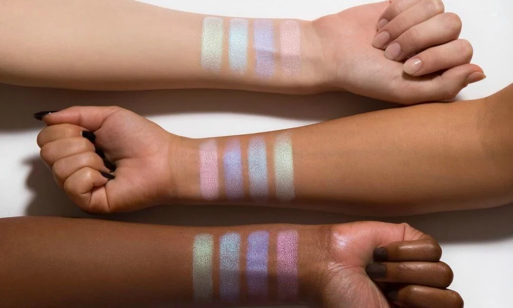 Three arms of different skin tones display pastel eyeshadow swatches in parallel rows-Best Makeup Products of 2026