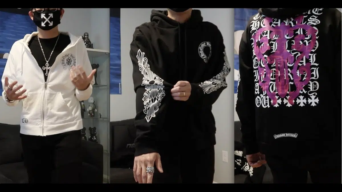 Three models showcase streetwear: a white zip hoodie and two black hoodies with ornate white and purple graphics, silver jewelry, and masked faces; edgy, bold style.
