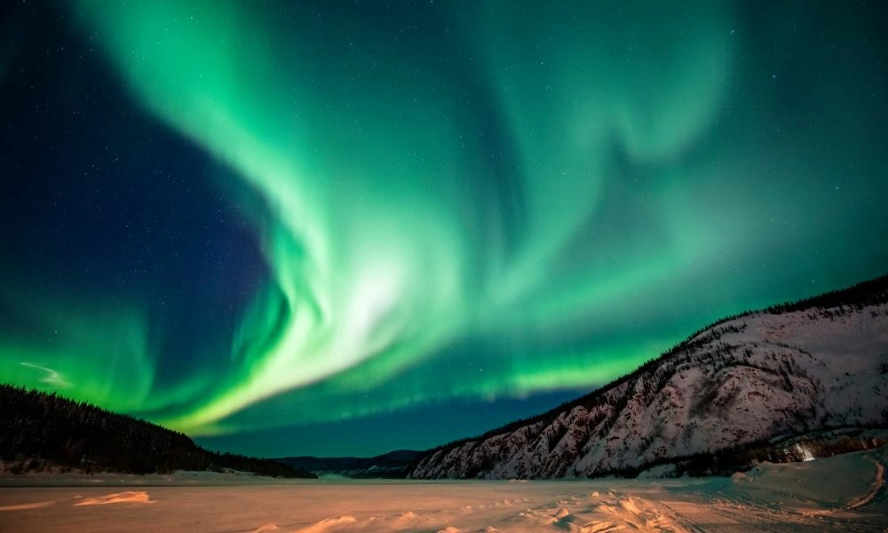 Vivid green aurora borealis sweeps across a dark night sky-Best Places to See the Northern Lights