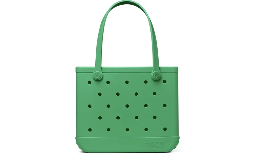 A bright green tote bag with long handles and evenly spaced round ventilation holes stands against a plain white background, giving a clean, playful look.