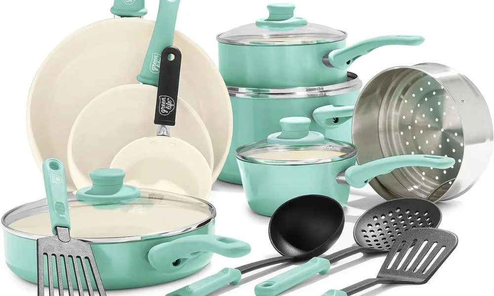 Mint-green cookware set with cream-lined pots, pans, glass lids, a metal colander, and matching utensils, arranged neatly on a white background.