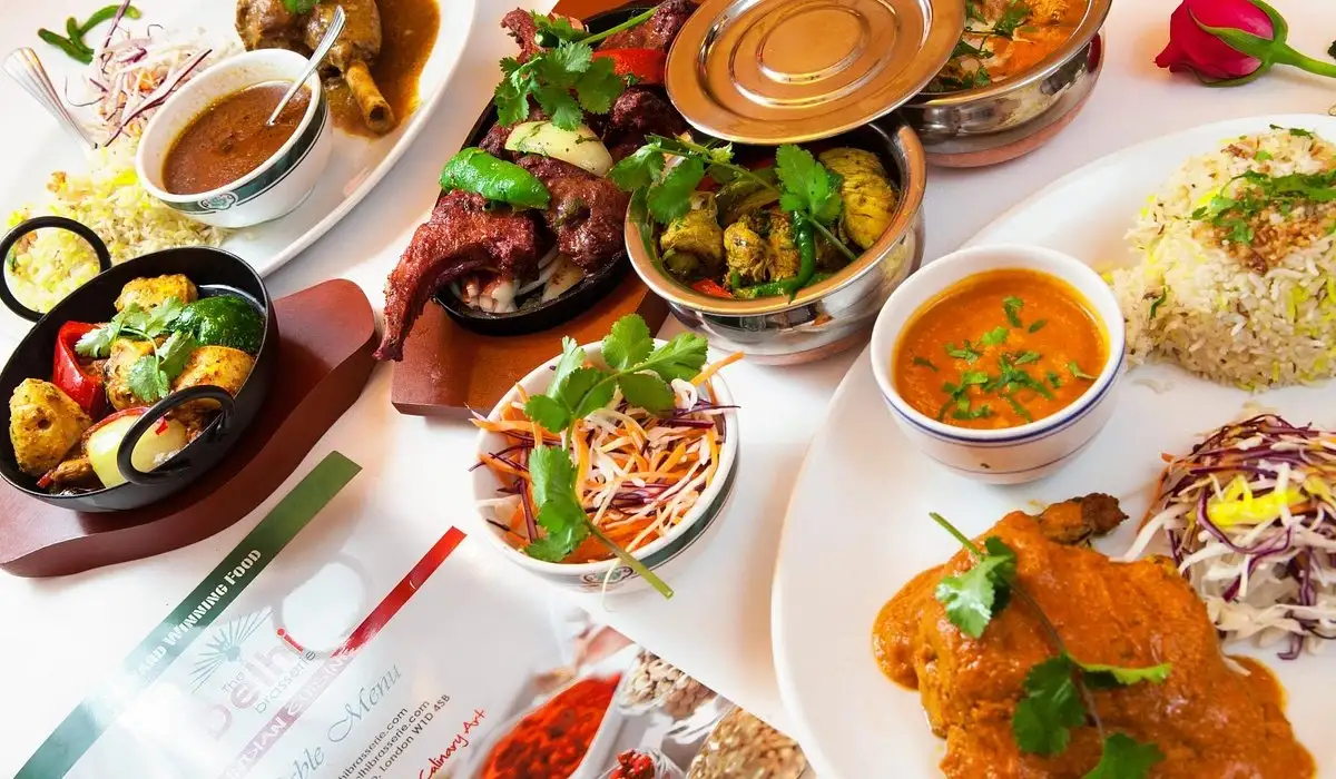 A vibrant Indian feast spread across a white table, with curries, rice, grilled meat, vegetables, chutneys, and fresh herbs, inviting and abundant.