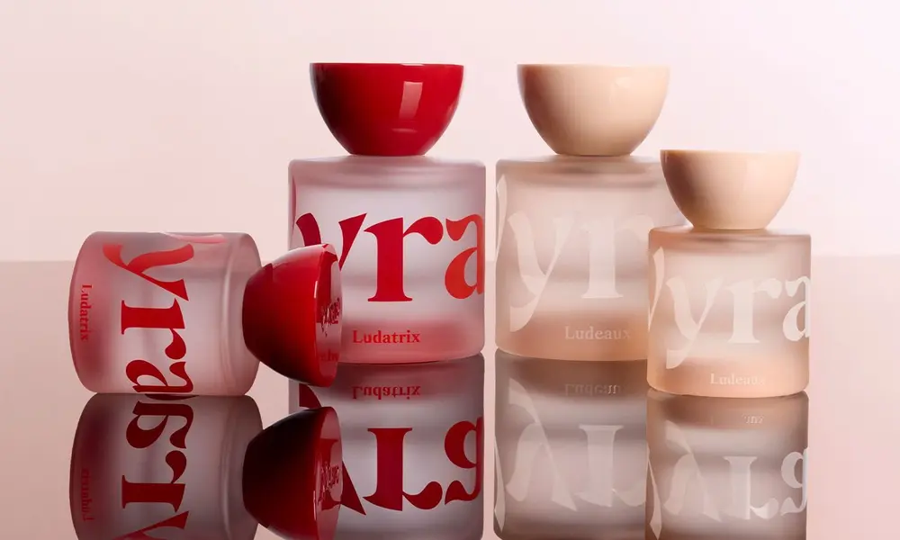 Luxury perfume bottles in red and blush glass stand on a reflective surface-Best Fragrances of 2026