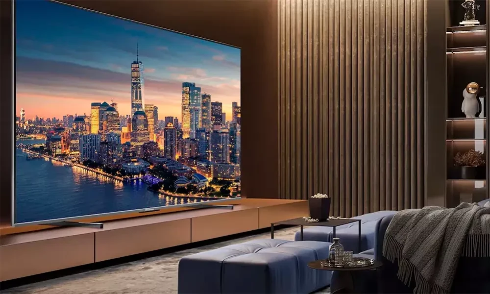 Modern living room with a large TV showing a glowing city skyline at dusk, blue sectional sofa, and warm wood paneling-Best Samsung TVs for a Luxury Home