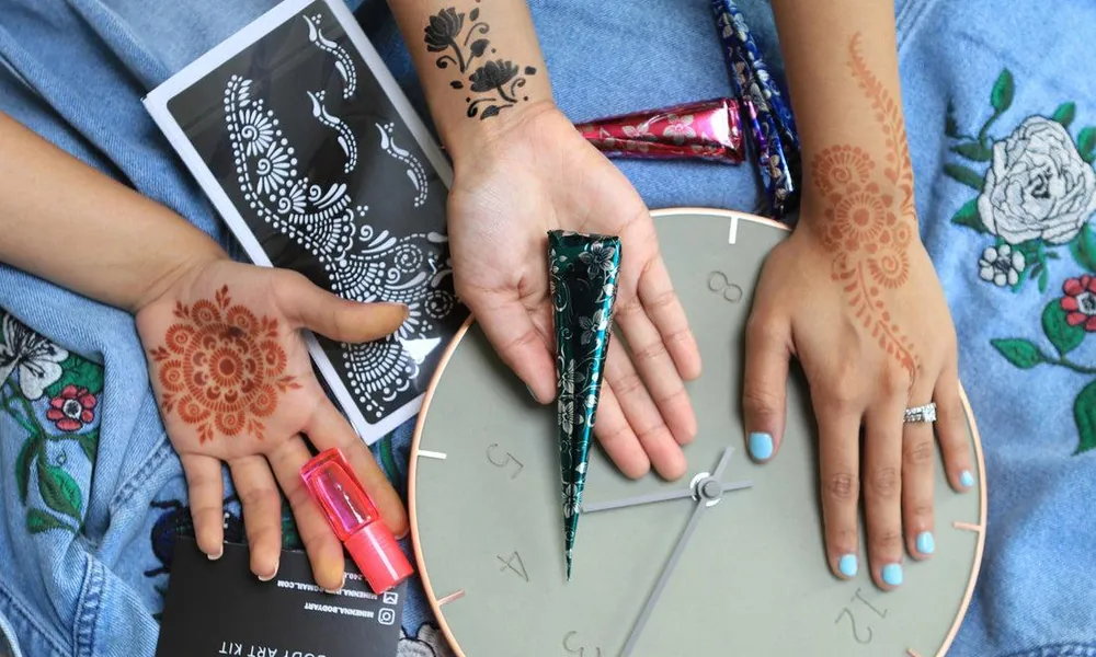 Woman applying water-transfer floral temporary tattoo to her arm with a damp cloth.