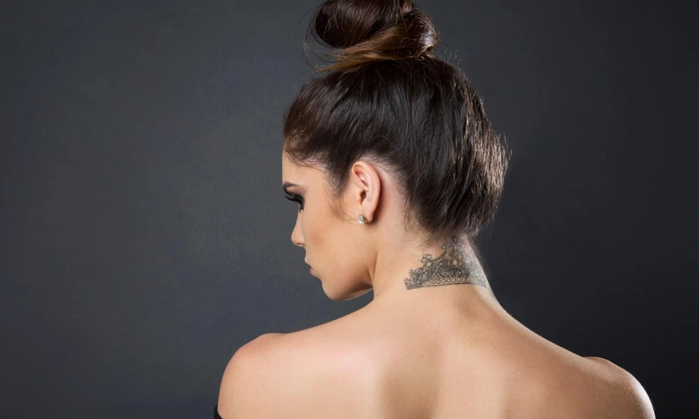 Ornate mandala pattern tattoo on the upper back of the neck.