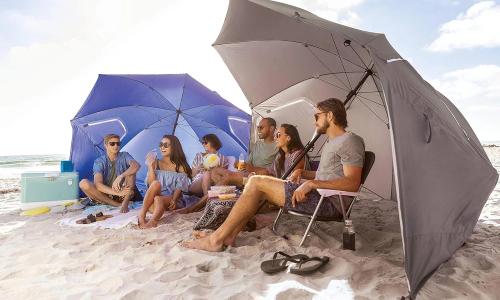 Family relaxing beneath a beach shelter with side panels