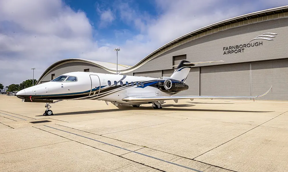 Cessna Citation Longitude midsize business jet parked outside a large aviation hangar