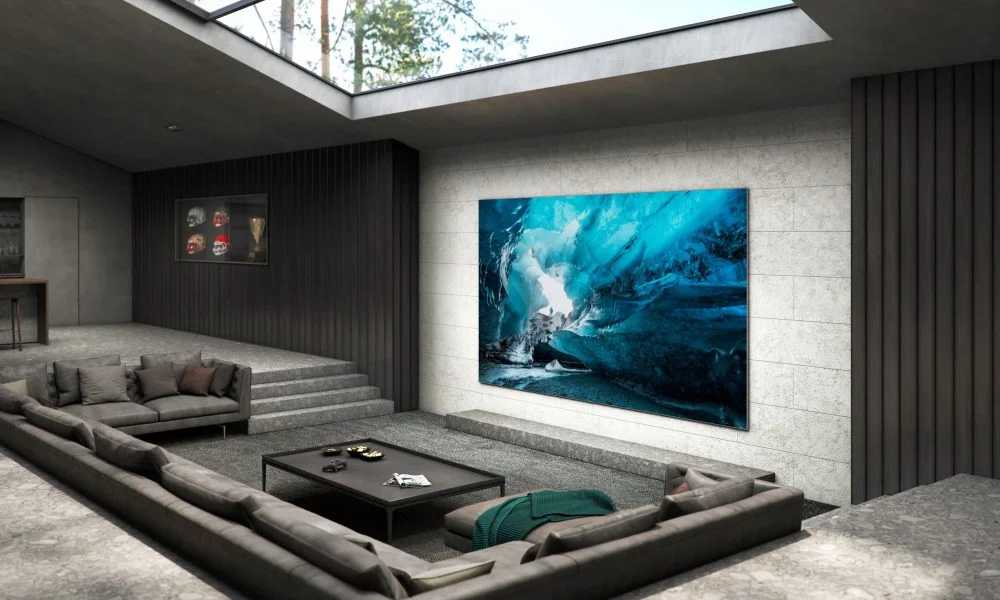 Modern concrete living room with a sunken gray sectional, black coffee table, vivid blue ocean artwork, and overhead skylight-Best Samsung TVs for a Luxury Home