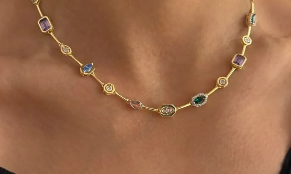 Luxury Fine Jewelry featured in a photo of a delicate gold station chain necklace set with colorful multi-shaped gemstones worn around the neck.