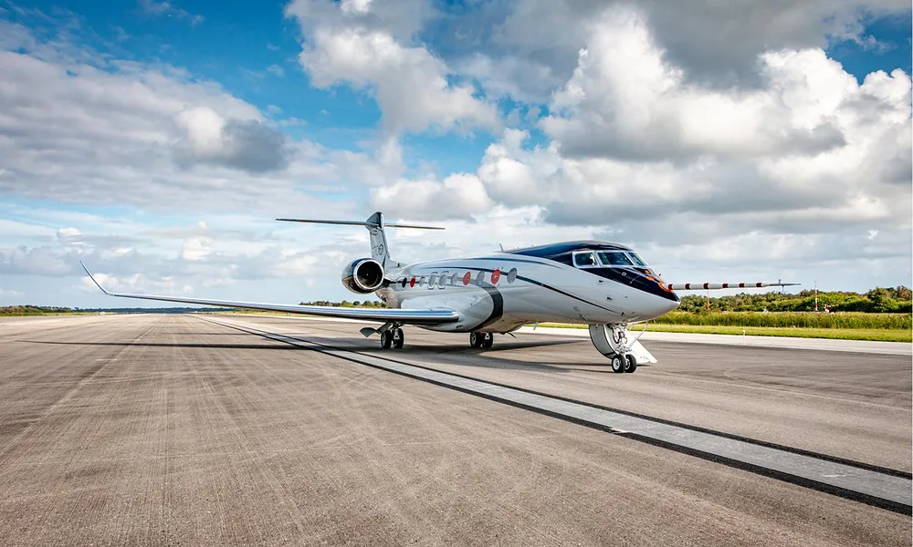 Gulfstream G700 flagship business jet parked on a runway under a partly cloudy sky