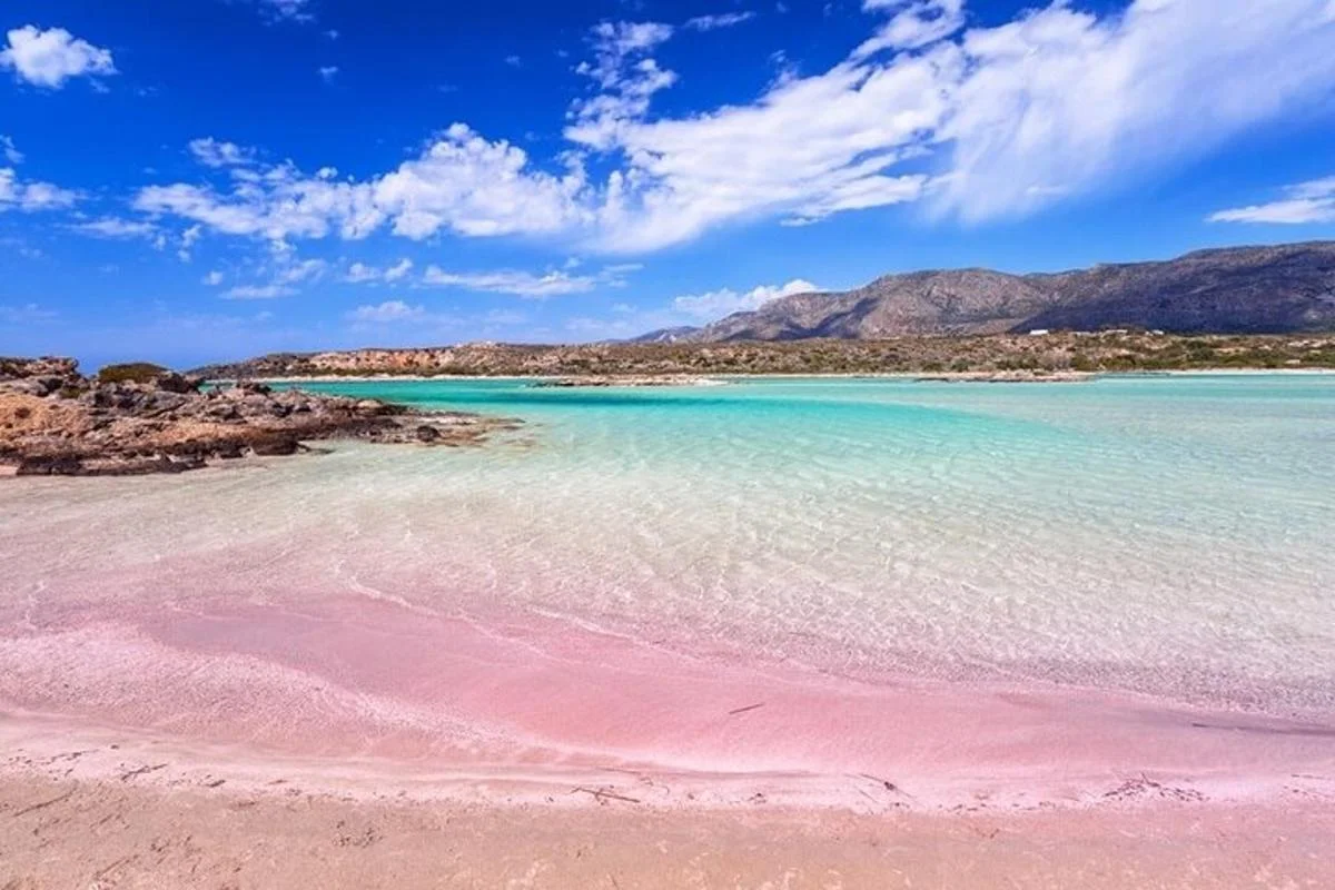 Pink sand coastline meets clear blue ocean water