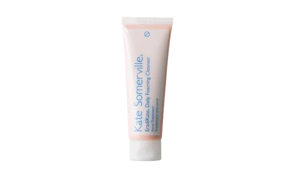 A slim white tube of Kate Somerville EradiKate Daily Foaming Cleanser stands upright against a black background, giving a clean, clinical feel.