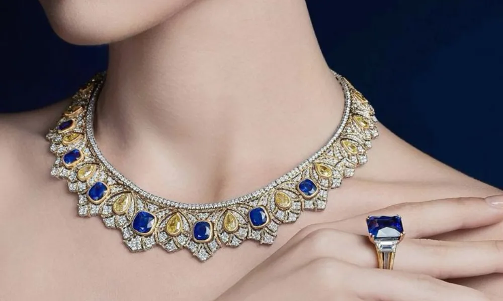 Luxury Fine Jewelry featured in a model portrait showcasing a sapphire and yellow diamond necklace, matching cocktail ring, and drop earrings.