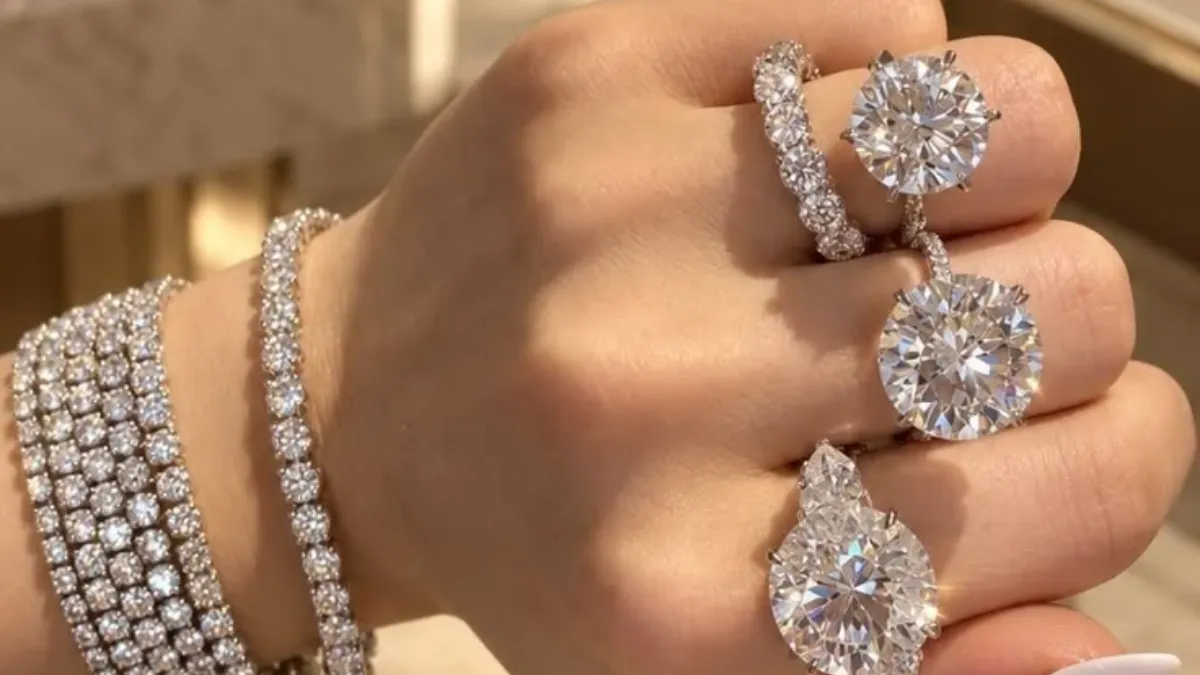 Luxury of Time by Diamonds International highlighted in an image showing a hand wearing multiple diamond rings and stacked diamond tennis bracelets.